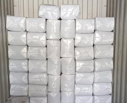 Wrapped white cocopeat bales stacked in even courses ready for loading.