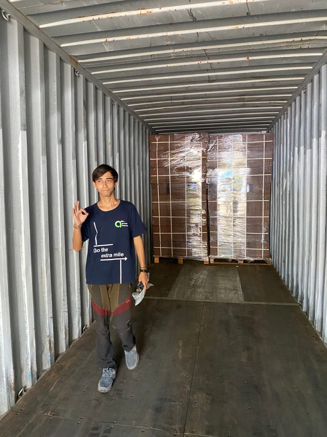 Agrorise Indonesia team member standing inside a container looking down its length towards the stowed pallets.
