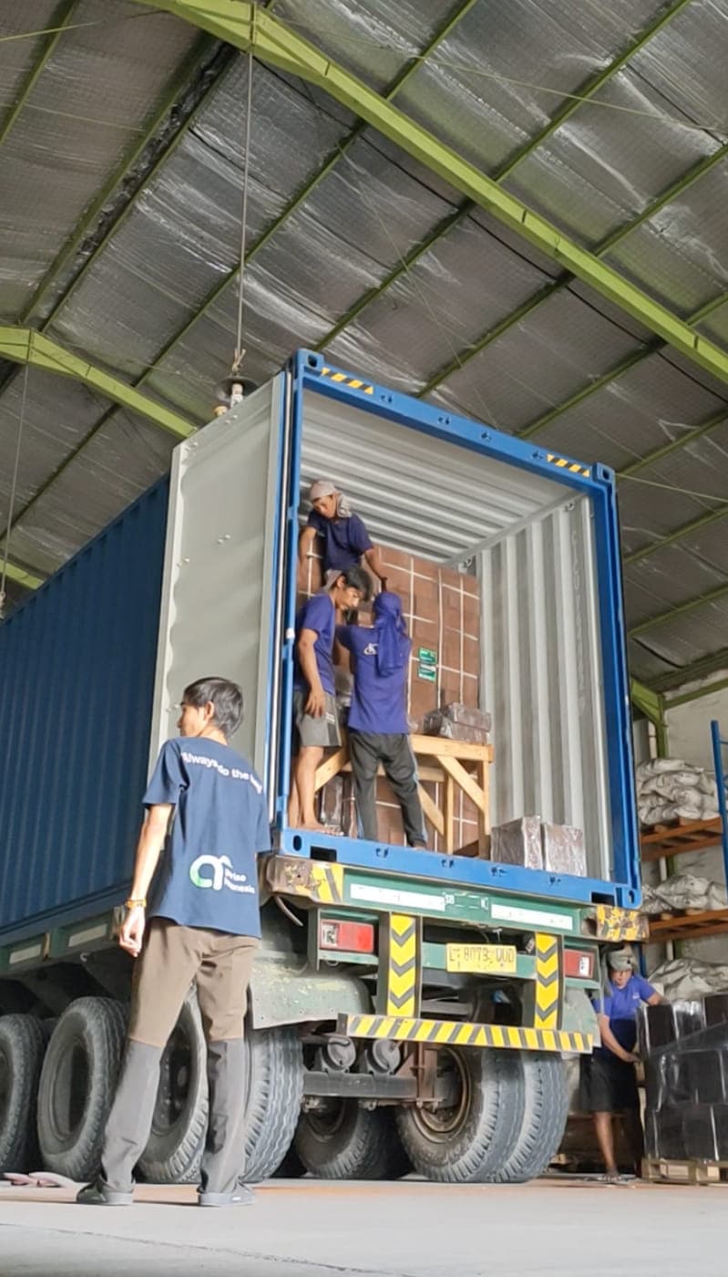 Agrorise Indonesia team members loading a container from a truck bed at the yard.
