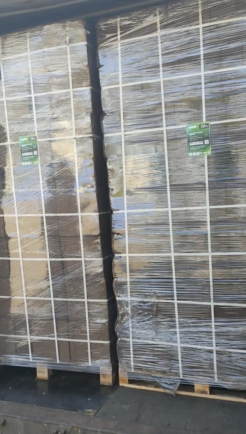 Wrapped pallets of cocopeat blocks stowed side by side inside a container.