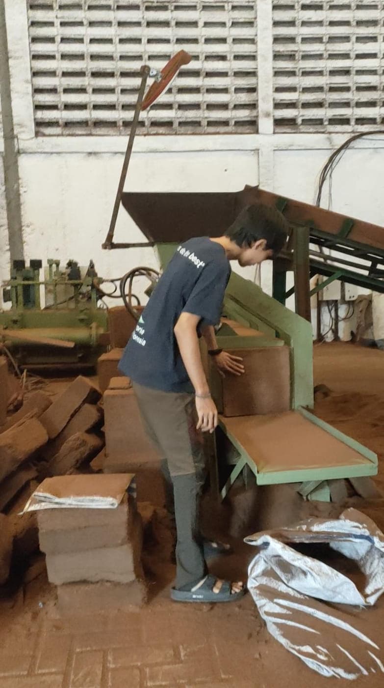 Agrorise Indonesia team member working at a cocopeat block press.