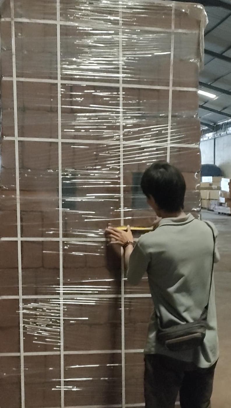 Agrorise Indonesia team member measuring a wrapped pallet of cocopeat blocks against a tape.