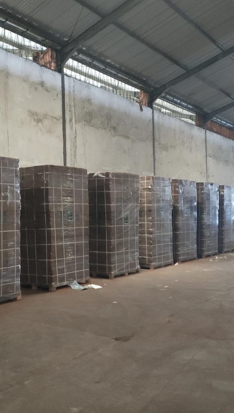 Rows of wrapped pallets of cocopeat blocks stored in a warehouse.
