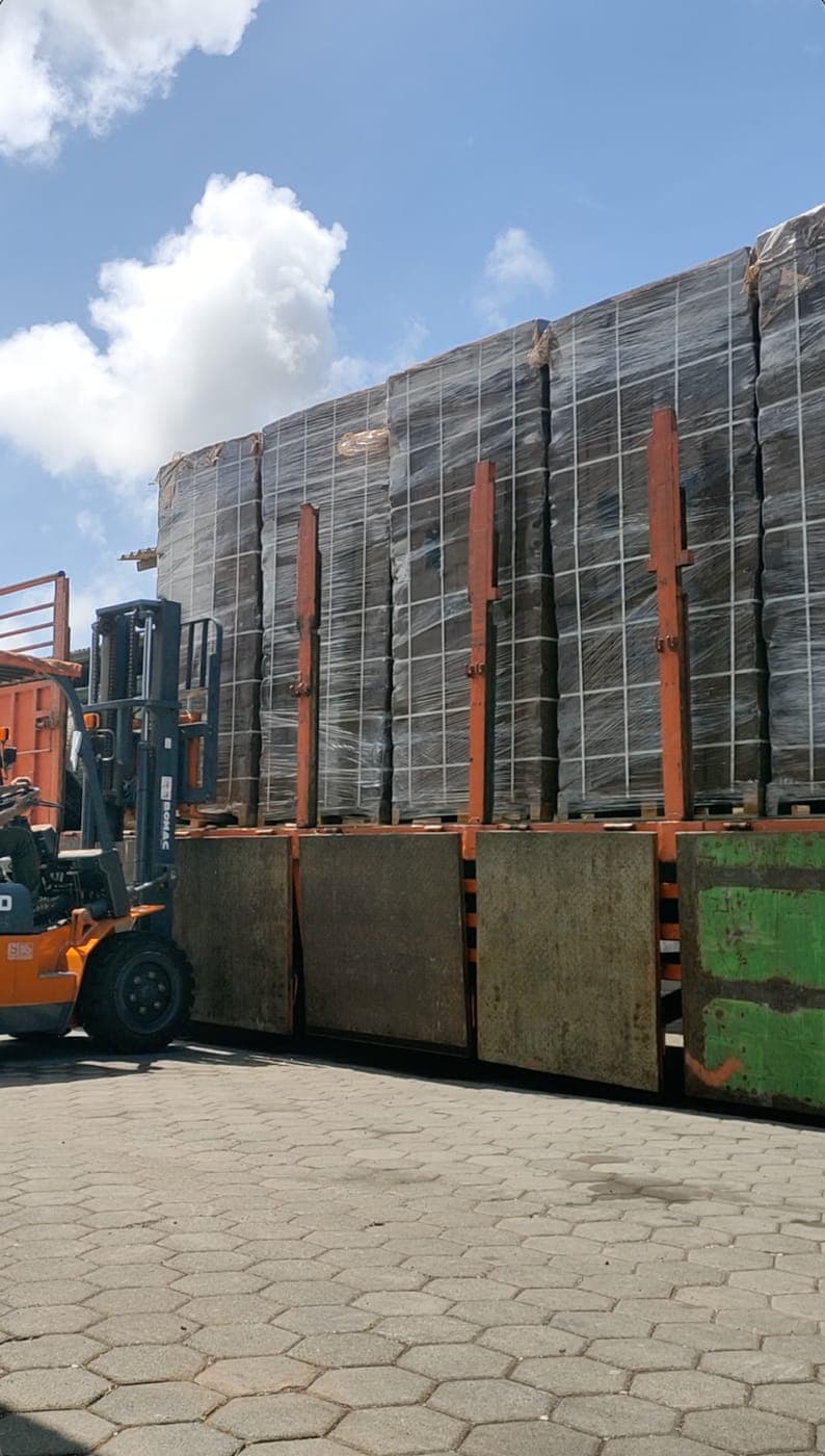 Palletised cocopeat blocks waiting in an open yard with a forklift alongside.