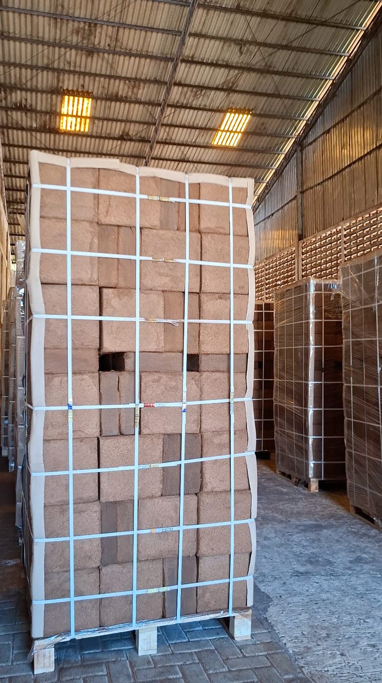 Wrapped and netted pallet of cocopeat blocks standing in a storage aisle.